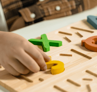Kind legt bunte Rechenzeichen aus Holz auf einen Tisch